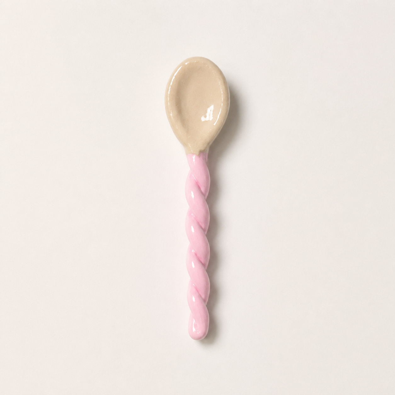 Pink handcrafted ceramic spoon with a twisted handle.